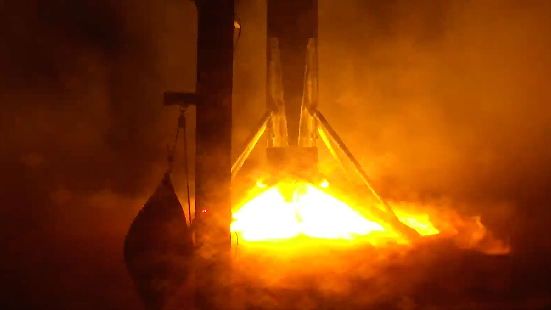 Яркое пламя двигателя Falcon 9 освещает ночной пейзаж во время посадки ступени на морскую платформу